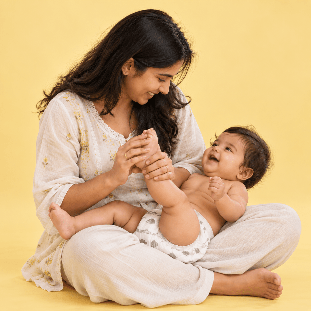 Mother playing with her laughing baby's feet, baby wearing a Lumi9 diaper
