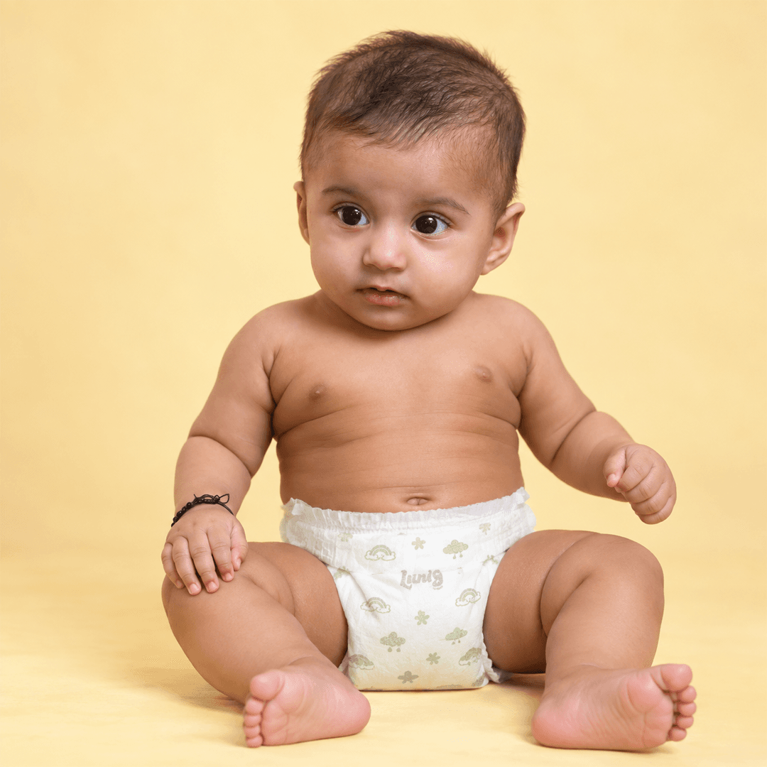 Mother smiling at her baby on the sofa, baby wearing a Lumi9 diaper